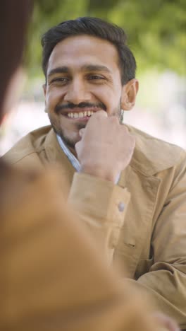 Vertical-Video-Close-Up-Of-Muslim-Couple-On-Date-Meeting-And-Talking-At-Table-On-City-Street-Together-4